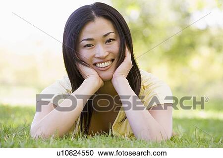 Stock Image - Woman lying outdoors smiling. Fotosearch