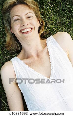 Woman lying outdoors smiling View Large Photo Image Stock Image - Woman lying outdoors smiling. Fotosearch