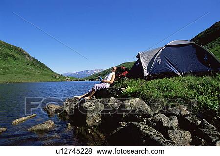 Woman outdoors at campsite sitting on large rocks by lake View Large Photo Image Stock Photo - Woman outdoors at campsite sitting on large rocks by lake. Fotosearch