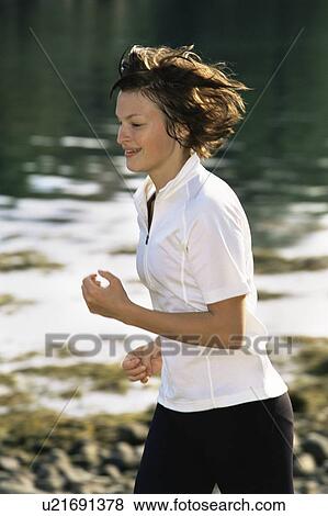 Woman outdoors by a stream running and smiling (selective focus) View Large Photo Image Stock Photo - Woman outdoors by a stream running and smiling (selective focus). Fotosearch