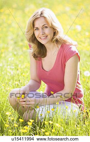 Woman outdoors holding flower smiling View Large Photo Image Picture - Woman outdoors holding flower smiling. Fotosearch