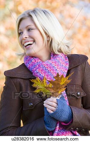 Woman outdoors in park holding leaf smiling (selective focus) View Large Photo Image Stock Photograph - Woman outdoors in park holding leaf smiling (selective focus). Fotosearch