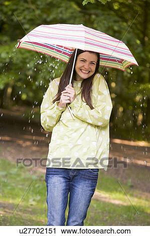 Woman outdoors in rain with umbrella smiling View Large Photo Image Stock Image - Woman outdoors in rain with umbrella smiling. Fotosearch