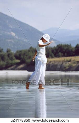 Woman outdoors walking in shallow water at beach (selective focus) View Large Photo Image Stock Image - Woman outdoors walking in shallow water at beach (selective focus). Fotosearch