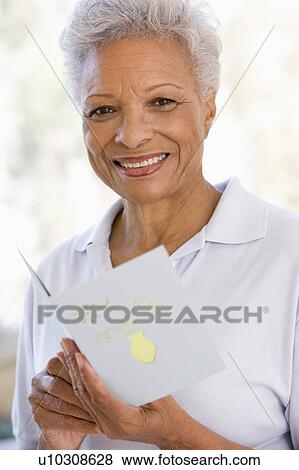 Stock Photo - Woman reading card and smiling. Fotosearch