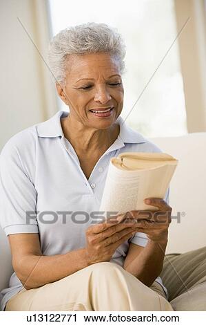 Stock Image - Woman relaxing with a book and smiling. Fotosearch