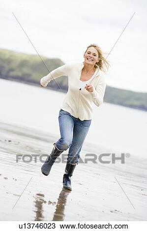 Woman running on beach smiling View Large Photo Image Stock Image - Woman running on beach smiling. Fotosearch
