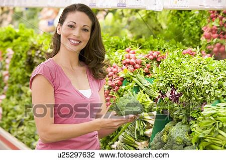 Woman shopping for broccoli at a grocery store View Large Photo Image Stock Image - Woman shopping for broccoli at a grocery store. Fotosearch