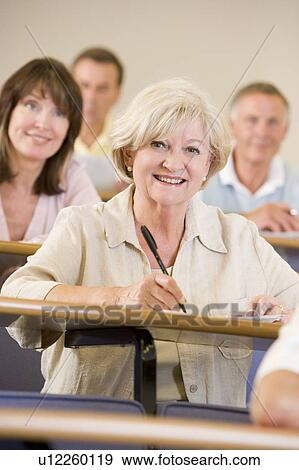 Woman sitting in adult classroom with students in background (selective focus) View Large Photo Image Stock Photo - Woman sitting in adult classroom with students in background (selective focus). Fotosearch