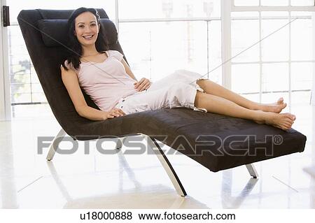 Stock Photo - Woman sitting in chair smiling. Fotosearch