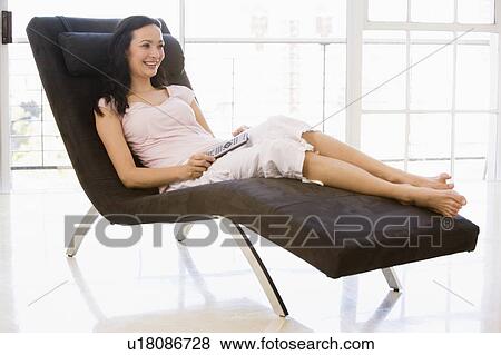 Woman sitting in chair with remote control smiling View Large Photo Image Stock Photo - Woman sitting in chair with remote control smiling. Fotosearch