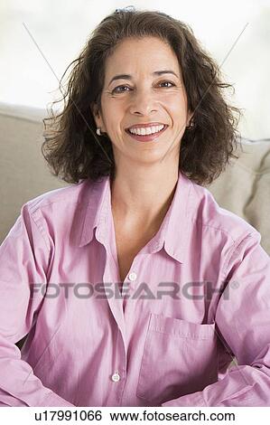Woman sitting in living room smiling View Large Photo Image Stock Photograph - Woman sitting in living room smiling. Fotosearch