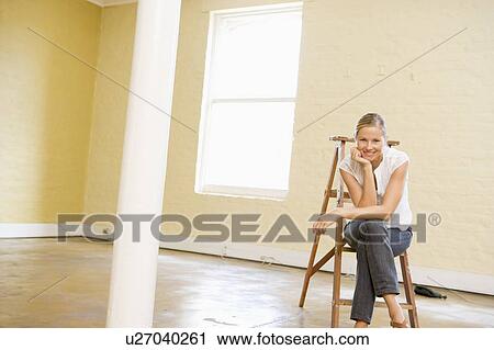 Woman sitting on ladder in empty space smiling View Large Photo Image Stock Image - Woman sitting on ladder in empty space smiling. Fotosearch