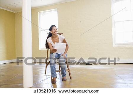 Woman sitting on ladder in empty space holding paper View Large Photo Image Stock Photograph - Woman sitting on ladder in empty space holding paper. Fotosearch