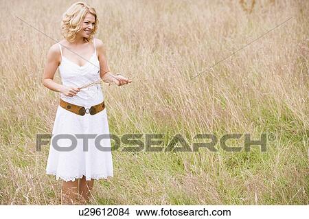 Woman standing outdoors holding grass smiling View Large Photo Image Picture - Woman standing outdoors holding grass smiling. Fotosearch