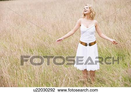 Woman standing outdoors holding grass smiling View Large Photo Image Stock Image - Woman standing outdoors holding grass smiling. Fotosearch