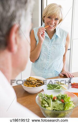 Stock Image - Woman Talking To Husband As She Prepares A meal, mealtime. Fotosearch