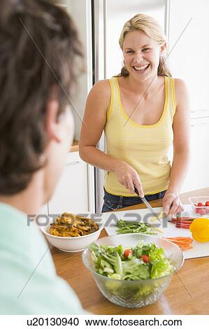 Stock Image - Woman Talking To Husband While Preparing meal, mealtime. Fotosearch