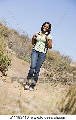 Stock Image - Woman walking on beach path smiling. Fotosearch