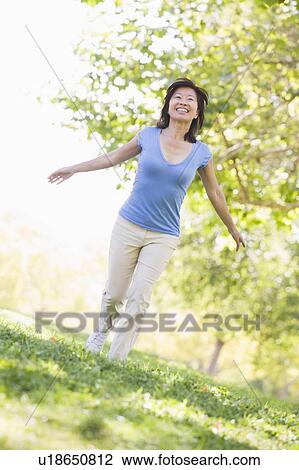 Stock Image - Woman walking outdoors smiling. Fotosearch