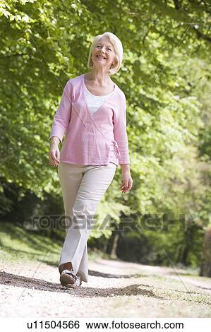 Woman walking outdoors smiling View Large Photo Image Stock Photograph - Woman walking outdoors smiling. Fotosearch