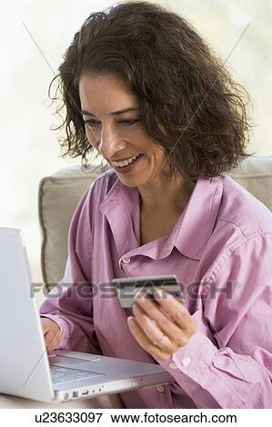 Stock Photo - Woman with a laptop computer making an online purchase with credit card. Fotosearch