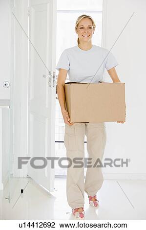 Woman with box moving into new home smiling View Large Photo Image Stock Image - Woman with box moving into new home smiling. Fotosearch