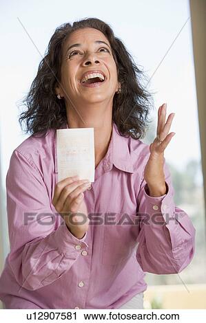 Stock Image - Woman with winning lottery ticket excited and smiling. Fotosearch