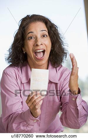 Stock Image - Woman with winning lottery ticket excited and smiling. Fotosearch