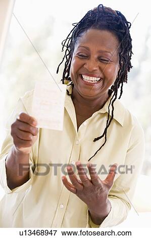 Stock Photo - Woman with winning lottery ticket excited and smiling. Fotosearch