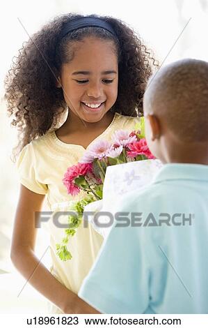 Young boy giving young girl flowers and smiling View Large Photo Image Stock Image - Young boy giving young girl flowers and smiling. Fotosearch