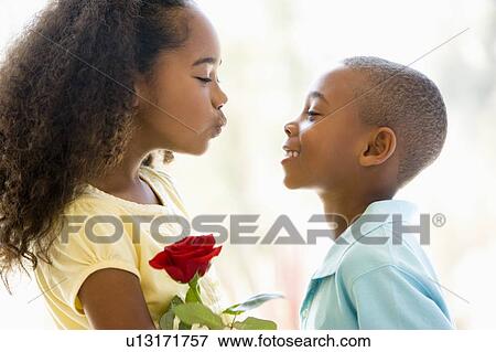 Young boy giving young girl rose and smiling View Large Photo Image Stock Photo - Young boy giving young girl rose and smiling. Fotosearch