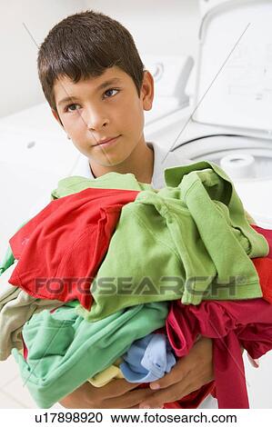 Stock Image - Young Boy Holding A Pile Of Laundry. Fotosearch