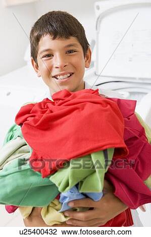 Stock Image - Young Boy Holding A Pile Of Laundry. Fotosearch