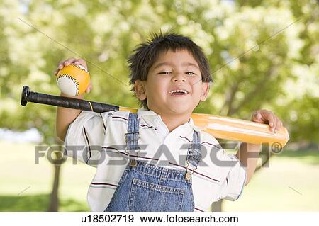 Young boy holding baseball bat outdoors smiling View Large Photo Image Stock Photo - Young boy holding baseball bat outdoors smiling. Fotosearch