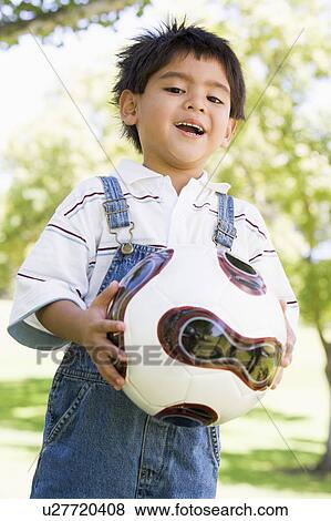 Young boy holding soccer ball outdoors smiling View Large Photo Image Stock Photo - Young boy holding soccer ball outdoors smiling. Fotosearch
