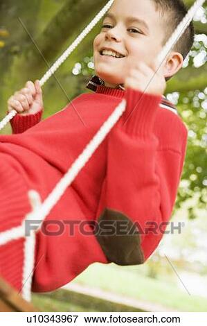 Young boy outdoors on tree swing smiling (selective focus) View Large Photo Image Stock Photo - Young boy outdoors on tree swing smiling (selective focus). Fotosearch