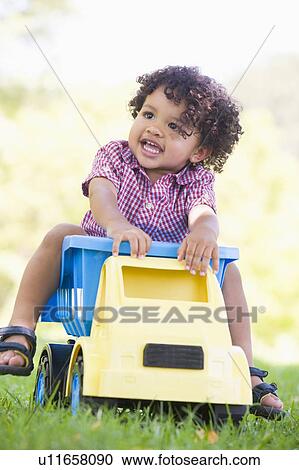 Young boy playing on toy dump truck outdoors View Large Photo Image Stock Image - Young boy playing on toy dump truck outdoors. Fotosearch