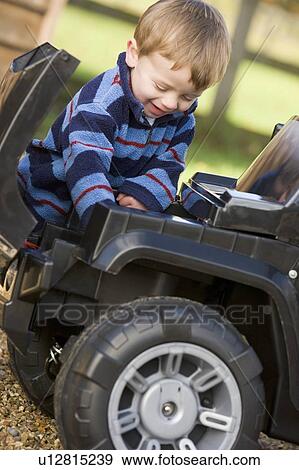 Stock Photo - Young boy playing outdoors with toy truck smiling. Fotosearch