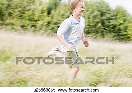 Stock Photography - Young boy running in a field smiling. Fotosearch
