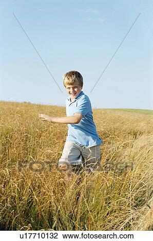 Stock Image - Young boy running outdoors smiling. Fotosearch