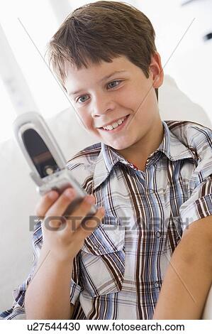 Young Boy Sitting On A Sofa Texting On A Mobile Phone View Large Photo Image Stock Image - Young Boy Sitting On A Sofa Texting On A Mobile Phone. Fotosearch