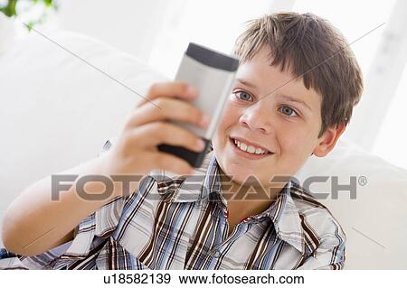 Young Boy Sitting On A Sofa Texting On A Mobile Phone View Large Photo Image Stock Photo - Young Boy Sitting On A Sofa Texting On A Mobile Phone. Fotosearch