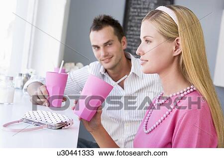 Young couple having a cold drink in a cafeteria View Large Photo Image Stock Image - Young couple having a cold drink in a cafeteria. Fotosearch