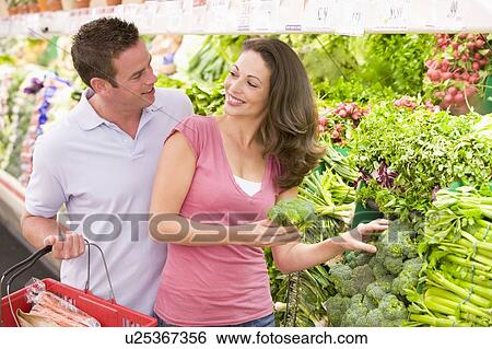 Stock Photograph - Young couple shopping for broccoli at a grocery store. Fotosearch