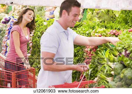 Stock Image - Young couple shopping for vegetables at a grocery store. Fotosearch