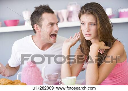 Stock Photo - Young couple sitting at a table arguing. Fotosearch
