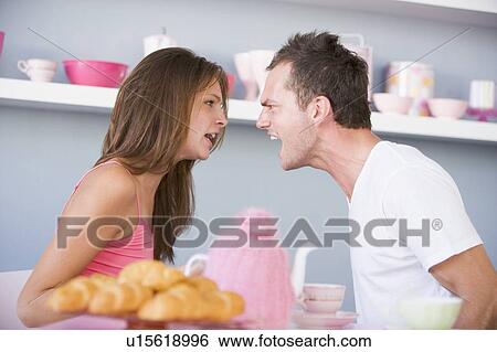 Stock Photograph - Young couple sitting at a table arguing. Fotosearch