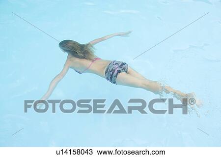 Stock Image - Young girl in swimming pool underwater. Fotosearch