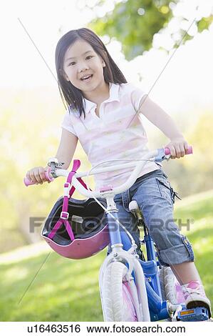 Young girl on bicycle outdoors smiling View Large Photo Image Stock Photograph - Young girl on bicycle outdoors smiling. Fotosearch